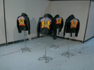 James Leonard - Back view of the installation, Warlords. Four chrome plated dress stands are posed in a corner of a gallery, each with its own black leather jacket which has been painted with a skull emerging from flames