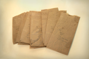 A group of brown paper lunch bags spread horizontally-each bag with hand-written note describing meal contents for the day, consumed by James Leonard during his A Kiss For Luck performance