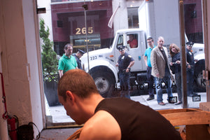 Onlookers watch as James Leonard carves away a wooden boat. Photo credit Jeff Geiringer.