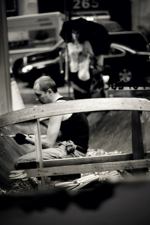 Woman with black umbrella watches as James Leonard carves away boat in A Kiss For Luck artwork 2013. Photo credit Wendy Whitesell.