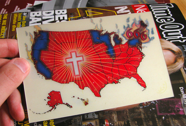 James Leonard - Depicting one angle of the Greetings From America lenticular postcard, outlining middle America as God country and liberal leaning edges as Satanic through the use of symbols: a cross and the numbers 666