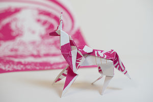 James Leonard - Pink origami unicorn with poster made of the same material posed in the background 