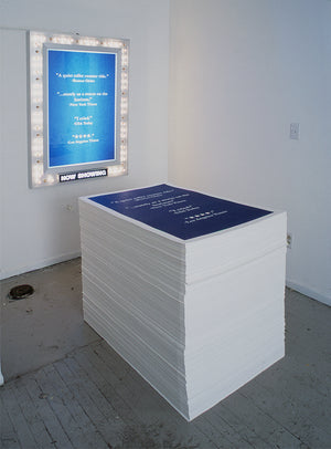 James Leonard - I Dream of Publicity installed in a gallery, with tall stack of takeaway movie posters on the ground and one hung and framed in glowing marquee lights behind