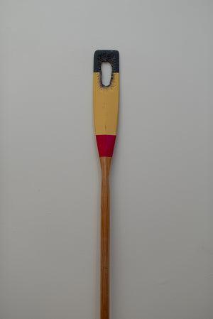 James Leonard - Photo of full-length Untitled Oar no. 3, which depicts horizontal black, yellow, and red stripes on the paddle