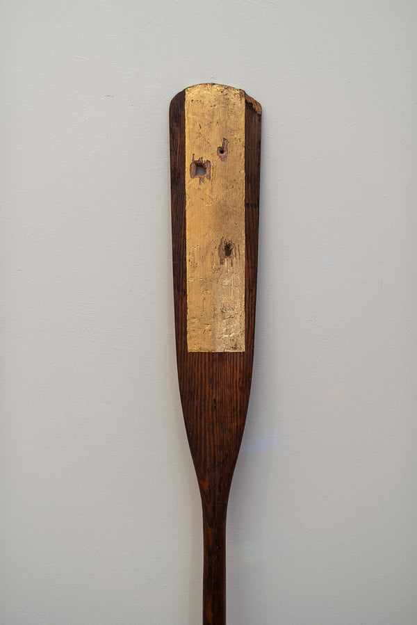 James Leonard - A crisp, gold rectangular shape is vertically positioned down the center of the paddle in Untitled Oar no. 7; within it, are three punctures that go entirely through the wood