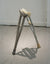 James Leonard - A pair of miniature fabricated crutches propped up against each other named, Two Monkeys Cudgel, are installed on the floor of a gallery space