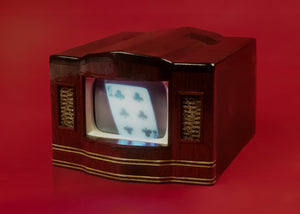 James Leonard - Detail of a miniature dark wood television set with gold trim used in Water Torture; a house of cards rebuilds itself on its screen