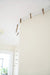 James Leonard - Running Fence no. 5, a miniature barbed wire fence, as it is hung across ceiling and cream colored wall