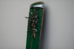 James Leonard - Detail image of the painted green paddle of Untitled Oar no. 9, centering a variation of nails that have been driven through it; a a metal harness keeps the split wood together